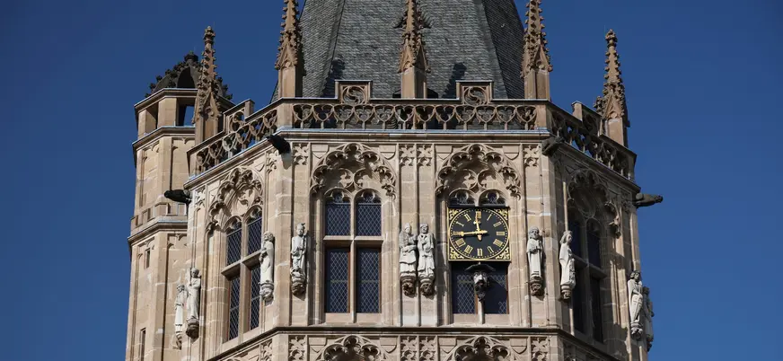 Detalle de la torre gótica del Ayuntamiento de Colonia con reloj y estatuas.