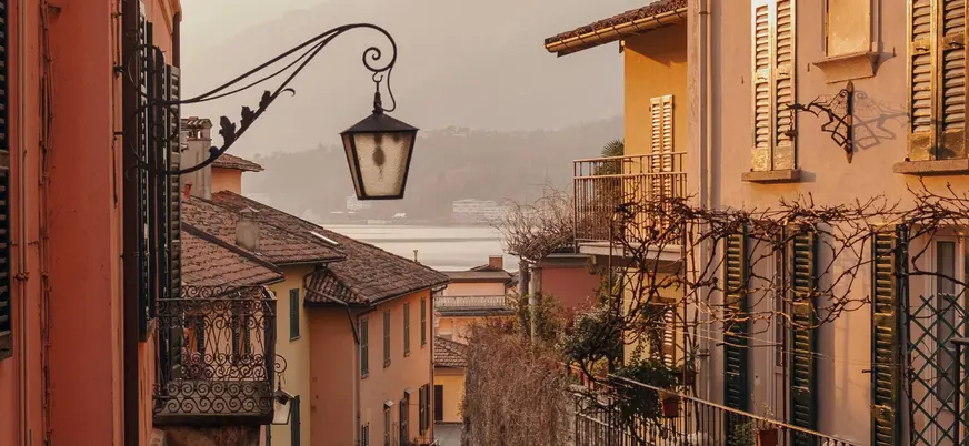 Calle con vista al Lago di Como al atardecer entre fachadas históricas