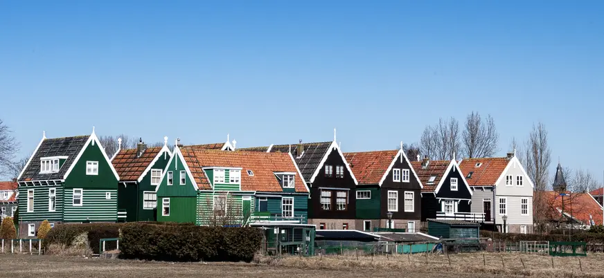 Casas tradicionales de Marken con fachadas de madera junto al campo.