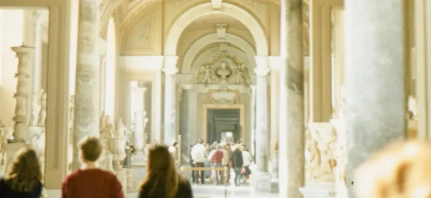 Pasillo luminoso de los Museos Vaticanos de Roma con visitantes caminando