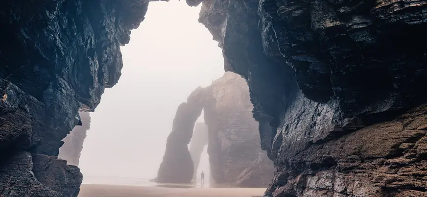 Vista interior de las cuevas y arcos naturales de la Playa de las Catedrales en un día de niebla, en la costa de Galicia.