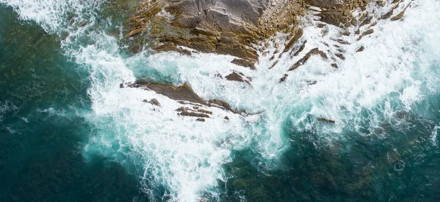 Olas rompiendo sobre rocas vistas desde arriba.
