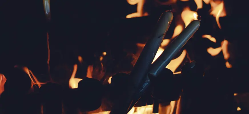 Ofrenda de velas de cera en la Capilla de las Apariciones en Fátima, Portugal, con llamas de fuego en la noche.