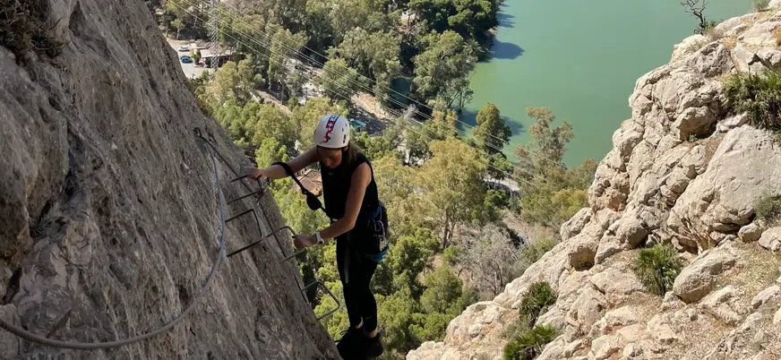 Mujer escalando en la vía ferrata Caminito del Rey frente al embalse