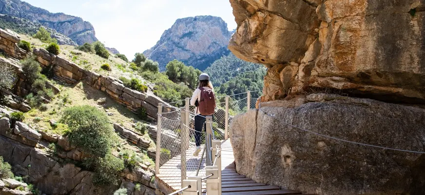Mujer con casco y mochila caminando por la pasarela del Caminito del Rey