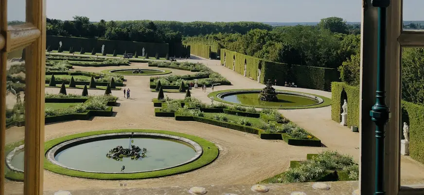 Vista del jardín exterior del Palacio de Versalles, con flores y arbustos bien cuidados en un entorno elegante.