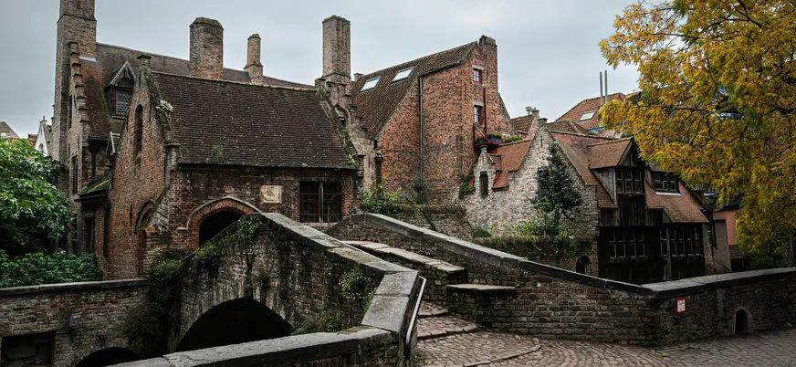 Puente de piedra sobre un canal con casas medievales de ladrillo en Brujas, Bélgica.