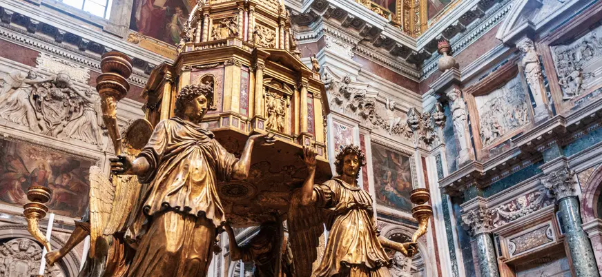 Escultura dorada de ángeles sosteniendo un relicario en un interior barroco de Roma