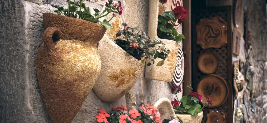 Macetas con flores colgadas en una pared de piedra en Santillana del Mar.