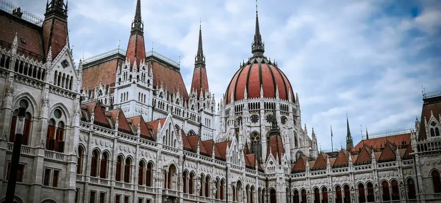 La fachada y cúpula del imponente Parlamento de Budapest bajo un cielo nublado.