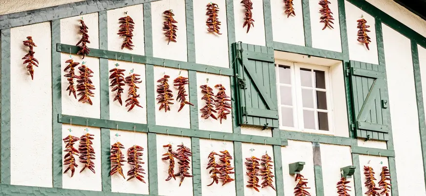 Fachada típica de Espelette decorada con pimientos rojos secándose, símbolo del País Vasco francés.