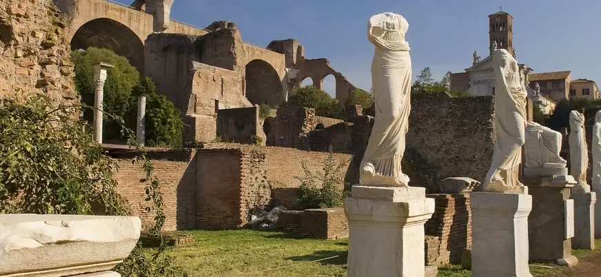 Estatuas y ruinas del Foro Romano en Roma, rodeadas de antiguos muros.