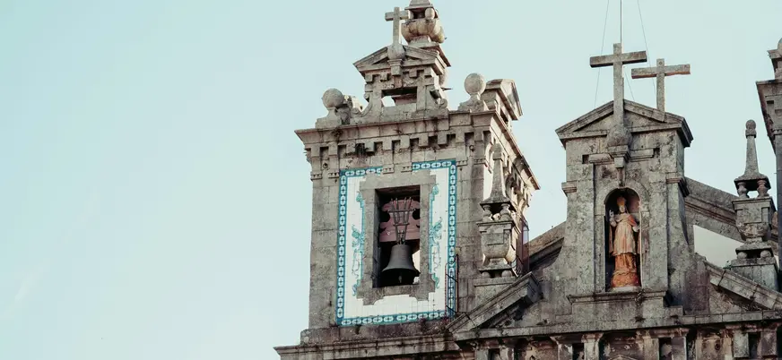 Campanario y fachada de una iglesia histórica en Oporto con detalles de piedra y azulejos.