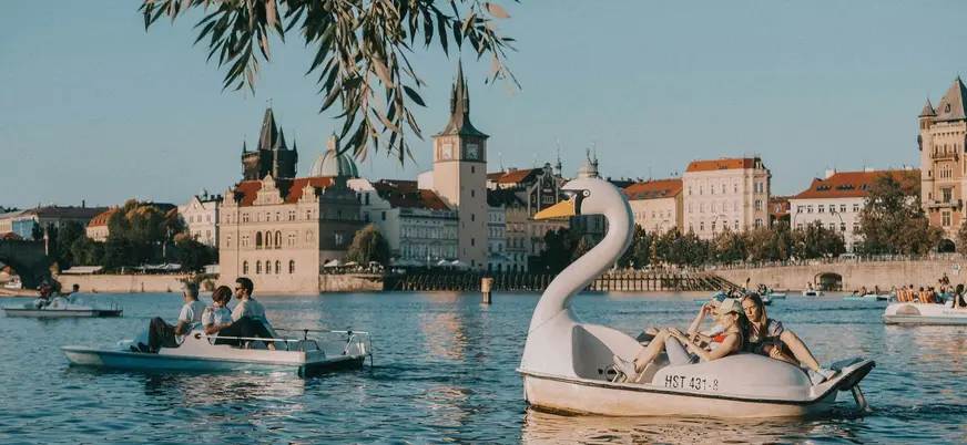 Gente navegando en hidropedales de cisne en el río Moldava con el horizonte de Praga.