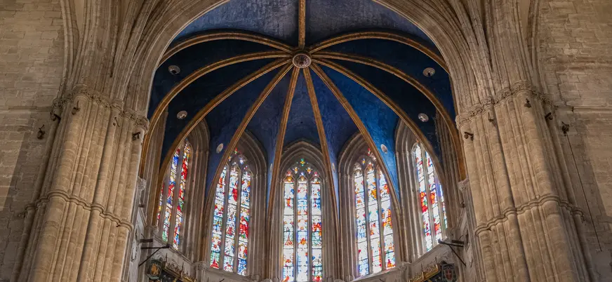 Interior de la Catedral de Oviedo, con su impresionante bóveda azul estrellada y vidrieras góticas llenas de color.