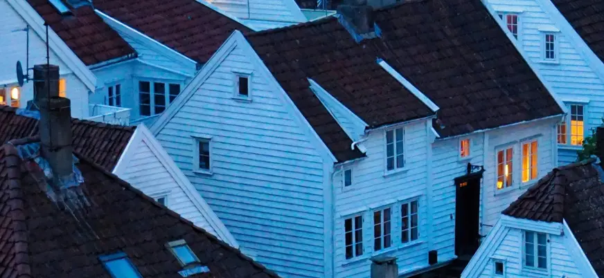 Casas tradicionales de madera blanca y tejados rojizos en Gamle Stavanger, Noruega, al atardecer.