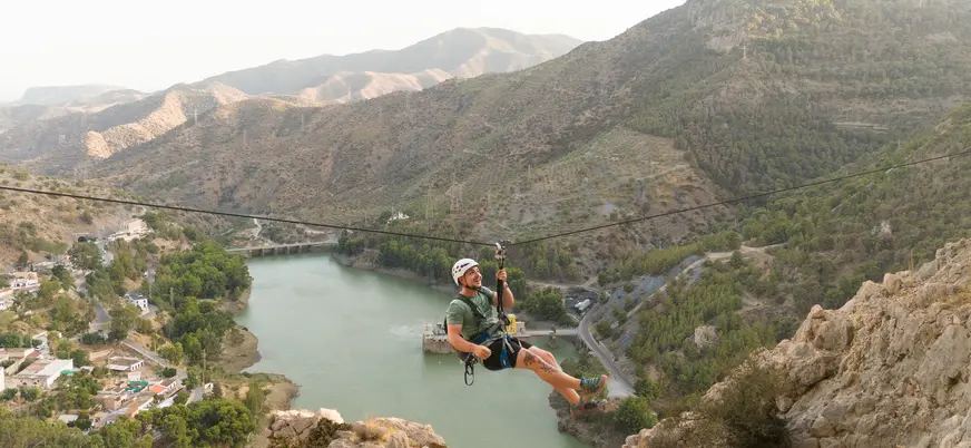 Hombre en tirolina sobre el embalse del Chorro, vía ferrata Caminito del Rey.