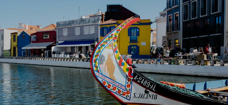 Moliceiro decorado navegando por un canal de Aveiro junto a casas coloridas.