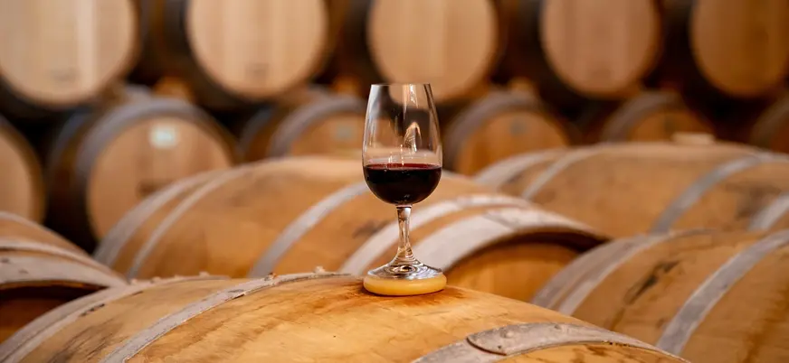 Copa de vino tinto sobre una barrica