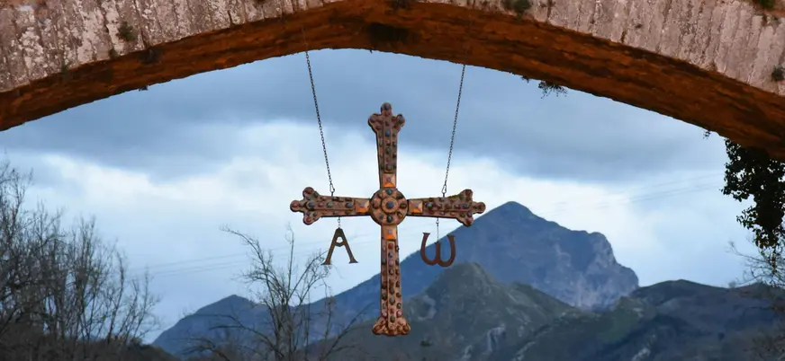 Cruz de la Victoria con montañas de Picos de Europa, colgada del Puente Romano en Cangas de Onís, Asturias.