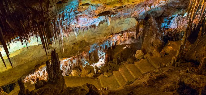 Escaleras de piedra entre estalactitas iluminadas en las Cuevas del Drach, Mallorca
