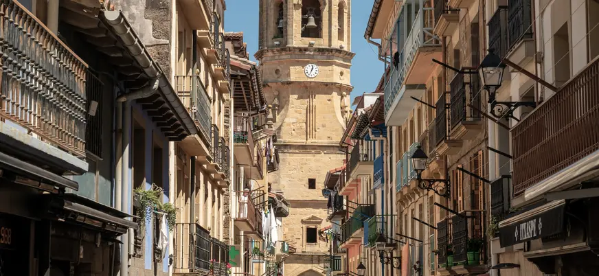 Calle principal de Getaria con casas tradicionales y torre de iglesia al fondo.