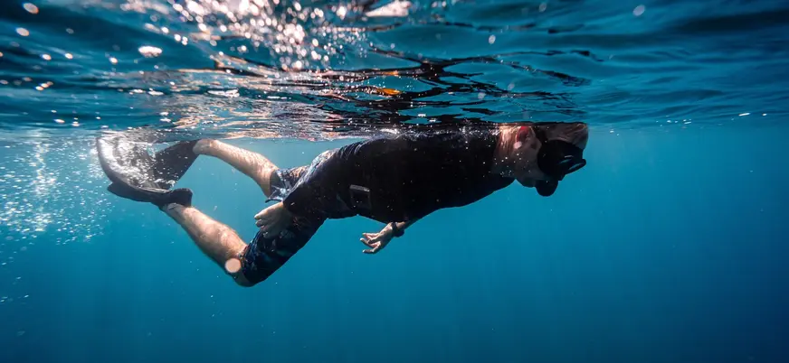Hombre buceando bajo la superficie del mar en Menorca, Islas Baleares