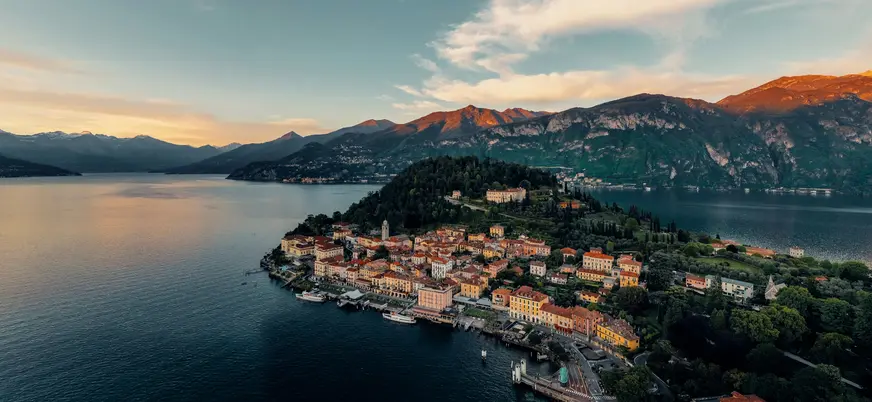 Vista aérea del Lago di Como al atardecer con pueblo costero y montañas