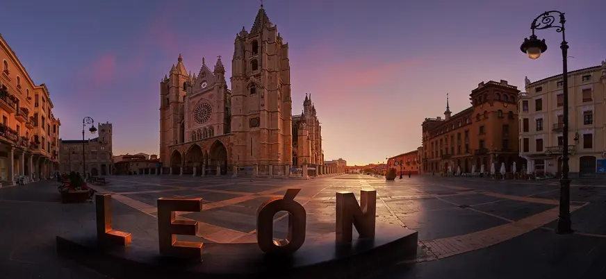 Catedral de León al amanecer, con el cartel de 'LEÓN' en primer plano, en la Plaza de la Regla, arquitectura gótica.