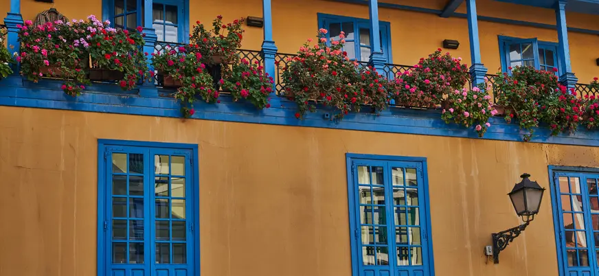 Fachada tradicional con balcones azules y flores en la Plaza del Fontán de Oviedo, uno de los rincones más emblemáticos.