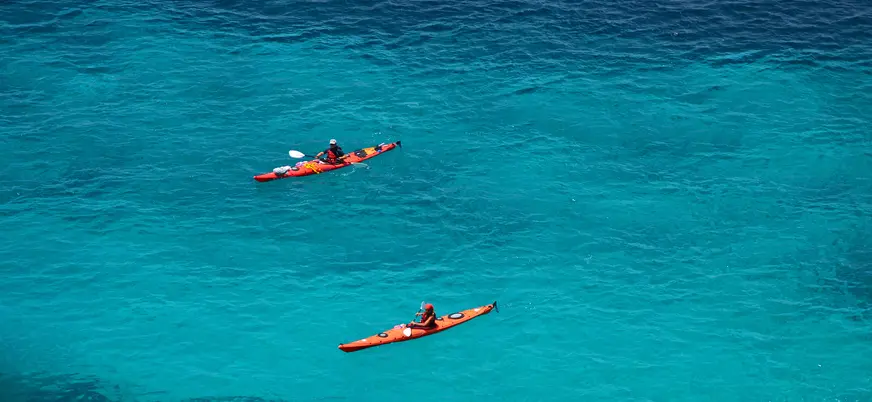 Kayaks rojos navegando por las aguas de Es Canutells, Menorca