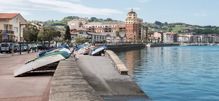 Barcas descansando junto al paseo marítimo de Hondarribia frente al agua y edificios.