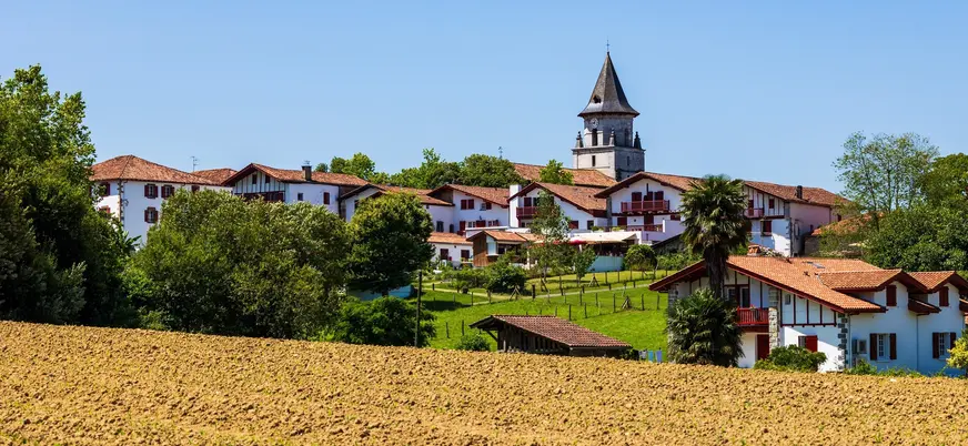 Pueblo de Bera con casas blancas y tejados rojos, rodeado de campos y la torre de su iglesia al fondo.