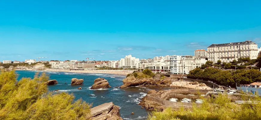 Vista costera de Biarritz con acantilados, playa y edificios junto al mar.