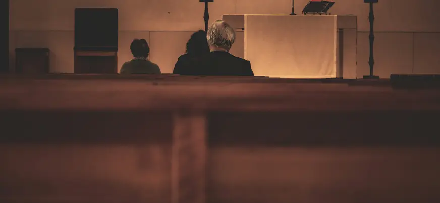 Fieles rezando o asistiendo a misa en una iglesia de Fátima, vista trasera de la congregación y el altar.