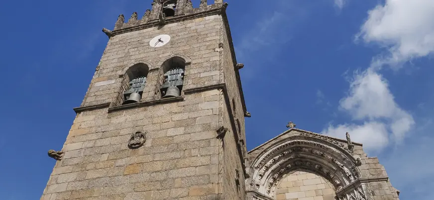 Torre y portada gótica de la Iglesia de Oliveira en Guimarães bajo un cielo azul.