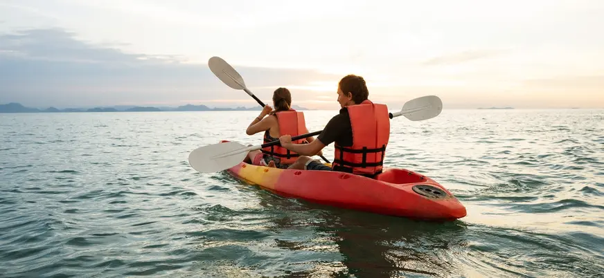 Pareja remando en kayak doble por la costa de Menorca