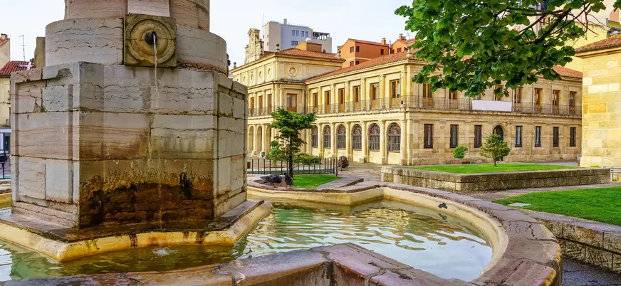 Fuente histórica en la Plaza San Isidoro, León, con el Real Colegiata de San Isidoro, arquitectura románica y jardines.