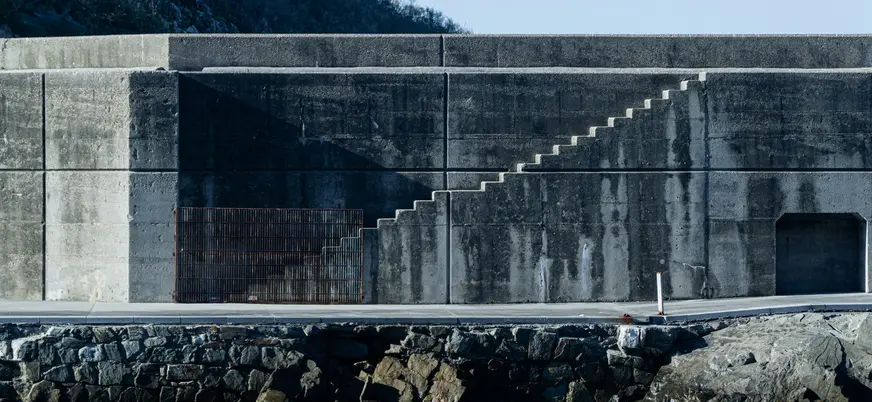 Muro de hormigón del rompeolas en el puerto de Cudillero, con escaleras geométricas y textura marcada por el mar.