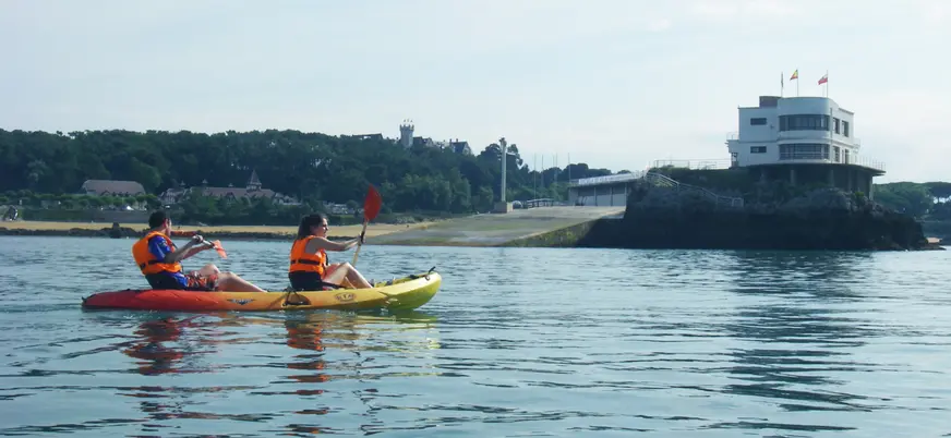 Pareja en kayak doble navegando frente a la Isla de la Torre en la bahía de Santander