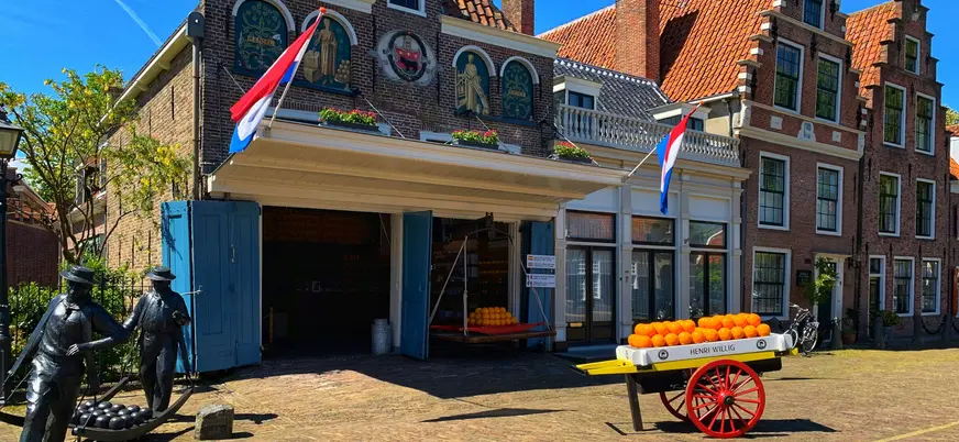 Entrada del mercado de quesos de Volendam con carro y estatuas típicas.
