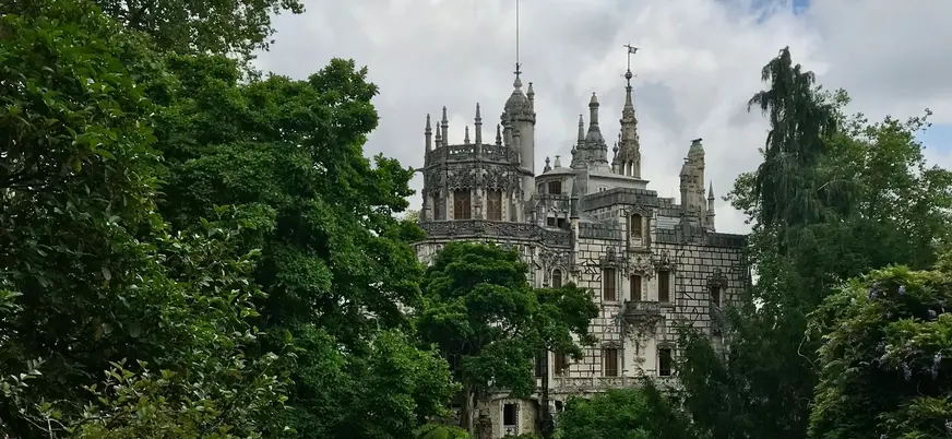 Vista del palacio de la Quinta da Regaleira entre árboles y jardines en Sintra.