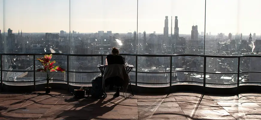 Persona trabajando en terraza con vistas panorámicas del skyline de Amberes, Bélgica, con edificios y torres altas.
