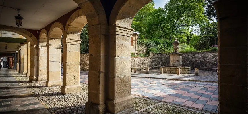 Arcos de piedra en la Plaza de Camposagrado, casco antiguo de Avilés, Asturias, con fuente y jardín