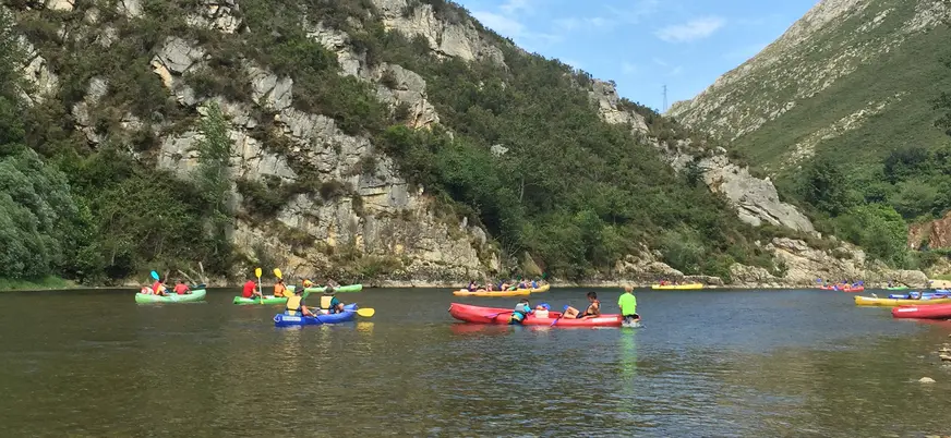 Grupo de piragüistas en canoas de colores por el río Sella, Asturias