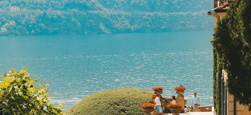 Terraza con flores y vista al Lago di Como frente a colinas frondosas