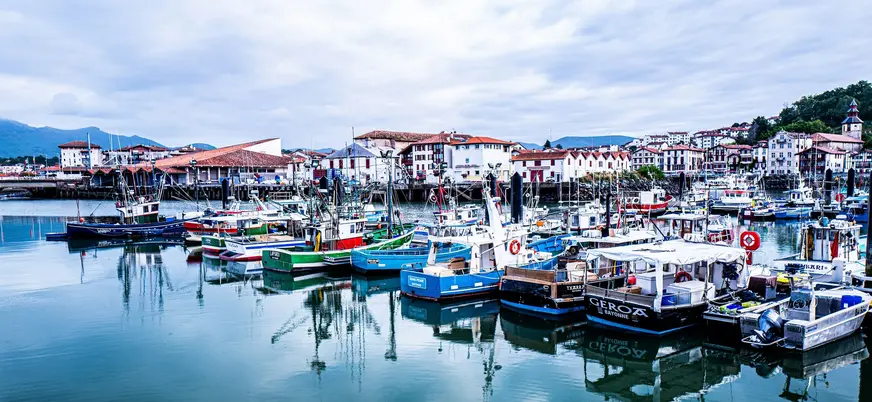 Puerto de San Juan de Luz con barcos de pesca y casas tradicionales junto al agua.
