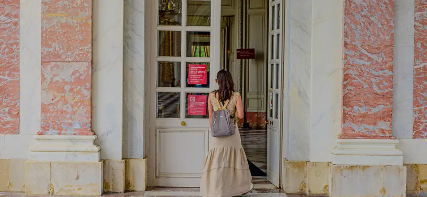 Mujer de pie frente a una puerta, con una expresión neutral y vestimenta casual.