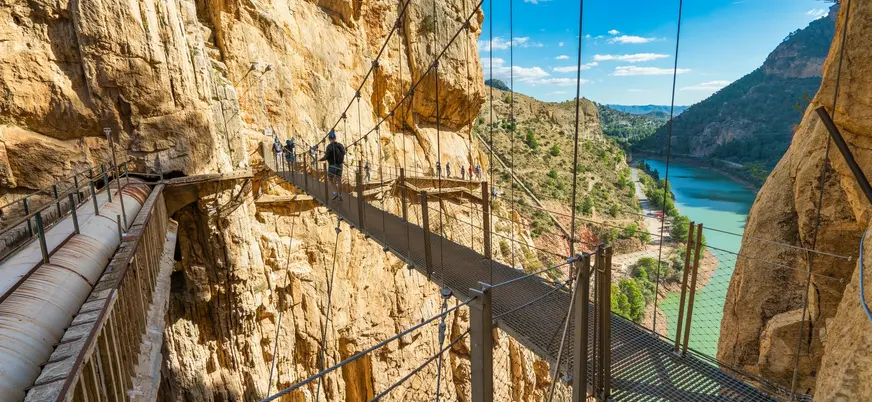 Puente colgante metálico del Caminito del Rey con vistas al embalse y las montañas