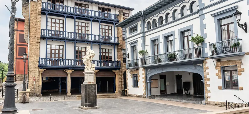 Plaza con estatua y edificios tradicionales con balcones en Guetaria.